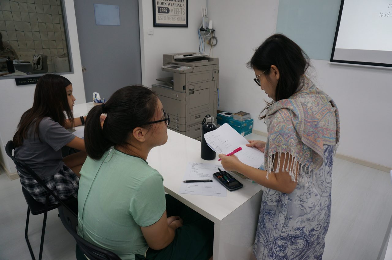 A Genius Plus Academy tutor guiding a Secondary student through marks-visible working